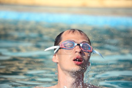 Young man in watersport goggles swimming in pool,