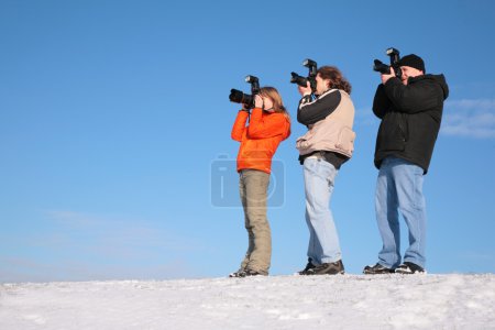 Three photographers on snow hill