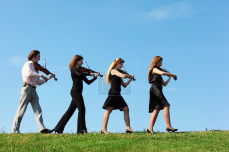 Four musicians go and playing violins against sky