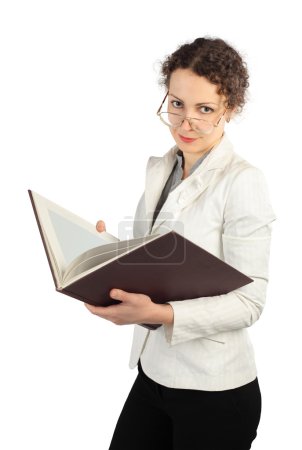 Young serious woman in glasses holding big book, looking at came