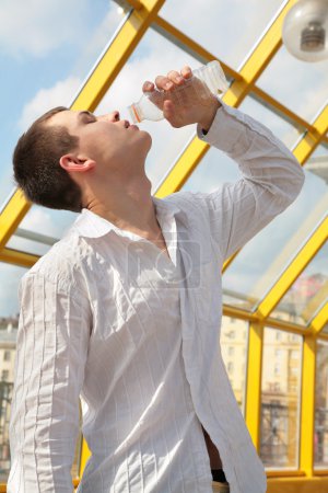 Boy drinks from bottle on footbridge