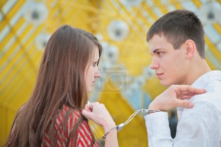 Young couple with handcuffs on footbridge