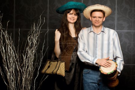 Young beautiful woman and smiling man in sombrero and with drum