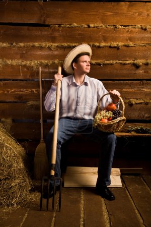 Young man with pitchfork,with basket of fruit and in straw hat