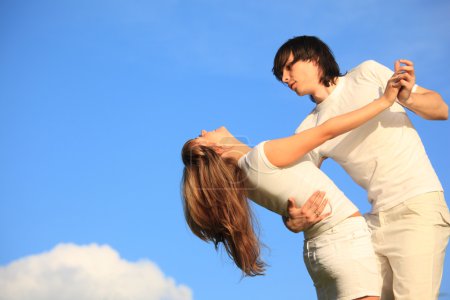 Guy holds girl for waist against sky