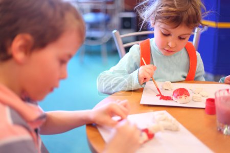 Children paint toys from clay