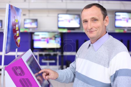Elderly man in shop at information screen