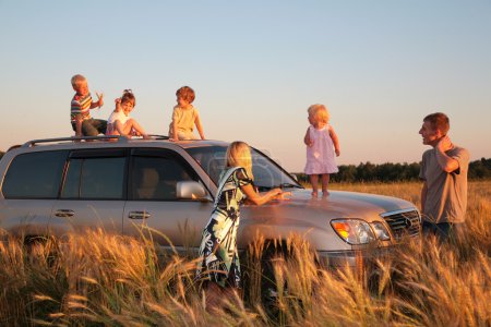 Parents and children on offroad car on wheaten field