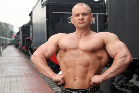 Athlete shows muscles against train