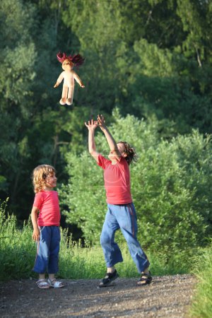 Boy and girl in park toss up upward doll