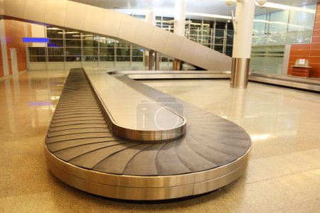 Empty baggage carousel in airport hall with granite floor and gl