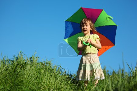 Girl with multicoloured umbrella in grass