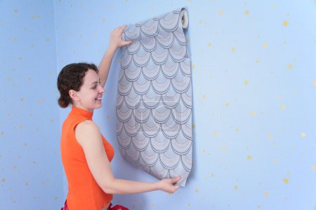 Young woman tries on wall-papers to wall