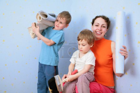 Children help mothrer to glue wall-papers