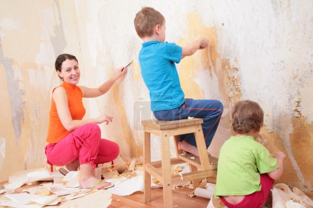 Children help mother remove old wallpapers