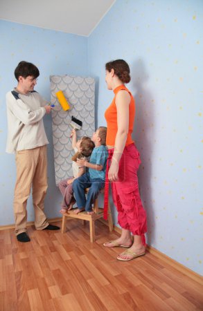 Children help parents to glue wall-papers
