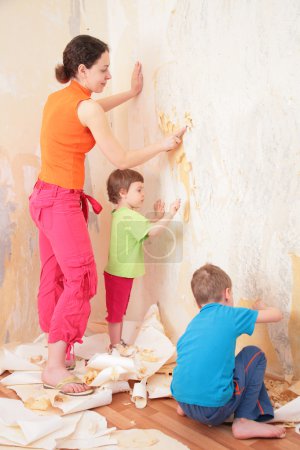 Children help mother remove from wall old wallpapers