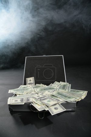 Suitcase with dollars against smoke