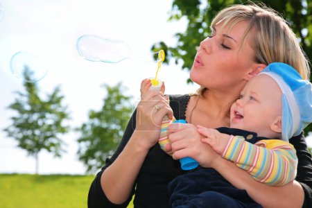 Mother with a child inflates soap bubbles