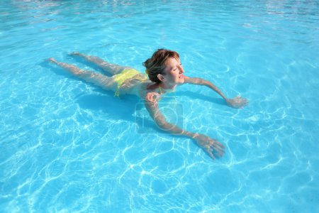 Young beautiful woman swimming in yellow bikini in paddling pool