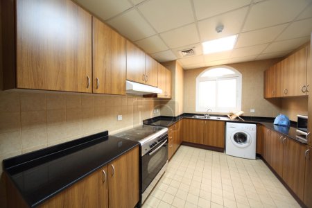 Kitchen with brown cupboards, washingmachine and cooker