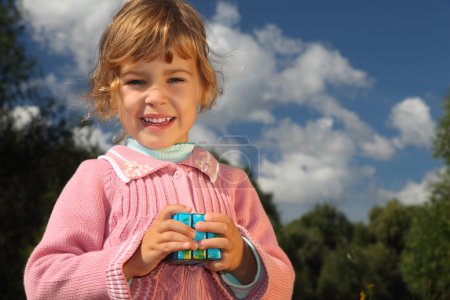 Little girl with magic cube outdoor in summer