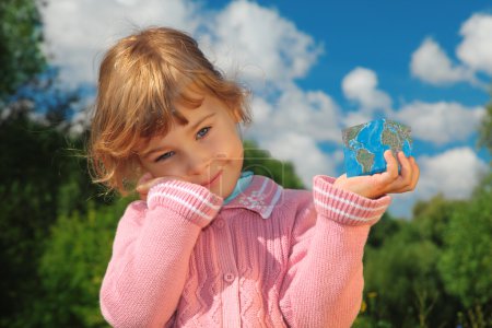 Little girl with Earth cube outdoor in summer