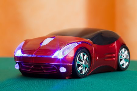 Computer mouse in form toy red sports car with glow headlights