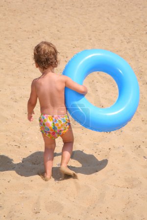The girl with a lifebuoy ring goes on sand