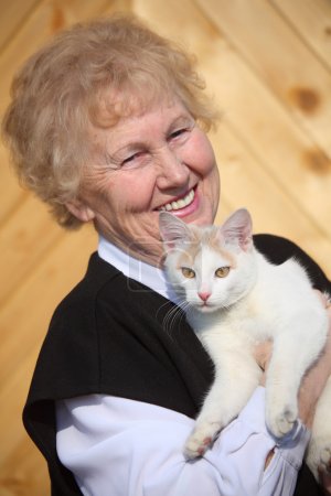 Smiling aged woman with cat on hands
