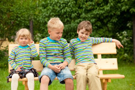 Three children on a bench in identical clothes