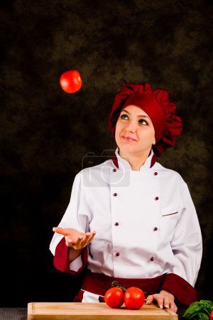 Chef juggling with tomato