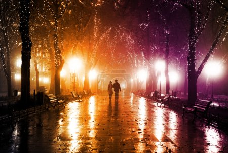Couple walking at alley in night lights.
