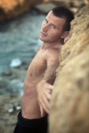 Attractive guy posing on rocks