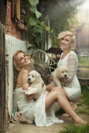 Perfect blonde beauties holding young dogs