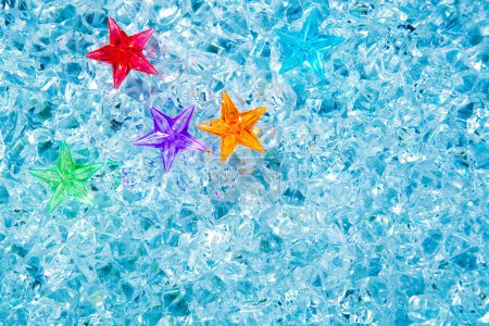 Christmas colorful glass stars on cold blue ice