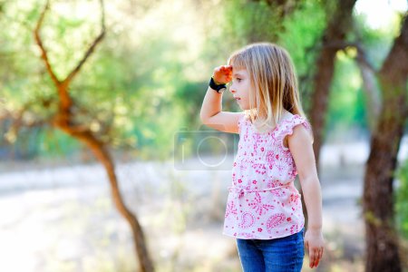 Hiking kid girl searching hand in head in forest