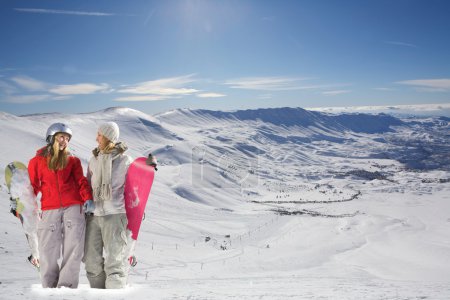 Two happy snowboarders in snow covered mountains