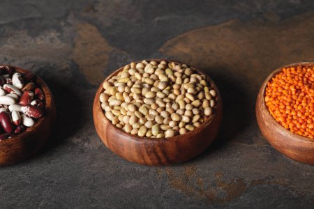 beans, soy and lentils in wooden bowls on table 