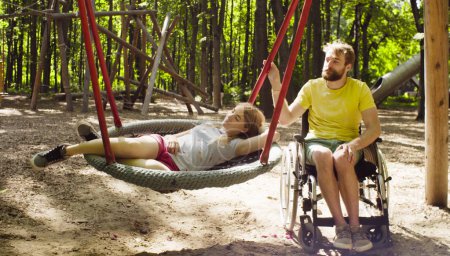 Woman is lying on a swing and a man is pushing a swing