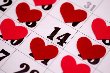 valentines day and holidays concept - close up of calendar sheet with 14th february date marked by red heart shape