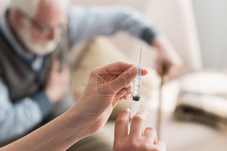 Selective focus of woman hands with syringe on elderly man background