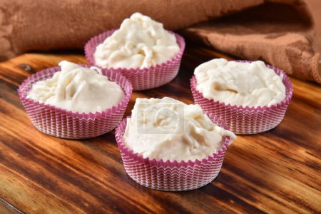 Gourmet coconut white chocolate cups on a wooden table