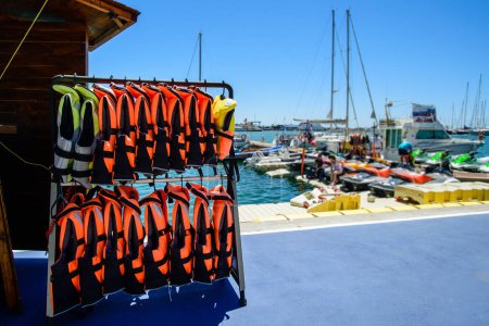 Many life jackets on the beach, safe motorboat rental, row of life jacket hanging for tourist services