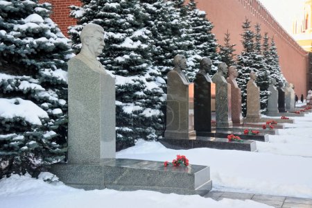 MOSCOW, RUSSIA - Jan 25, 2018 The line of tombs of Soviet leaders (Stalin's tomb in foreground) and blue pine trees covered snow in winter along the wall of Moscow Kremlin at the necropolis at Red Square. necropolis at the Red Square.