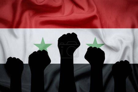Black silhouette Hands raised up and clenched in a fist against the background of the Syria flag. Concept of unity of the people of Syrian, revolution, revival, riot