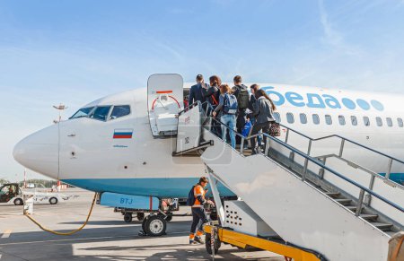11 MAY 2018, MOSCOW, RUSSIA, VNUKOVO AIRPORT: Passengers on the ladder boarding the airplane of the lowcost airline Pobeda
