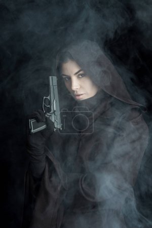 woman in death costume holding gun and looking at camera on black