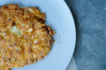 Crispy Thai omelet pork in blue ceramic plate. It's popular traditional, Thai style food