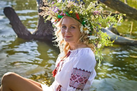 Beautiful  girl in national Ukrainian embroidery shirt and wreath of wild flowers. Holiday of Ivan Kupala in Ukraine.